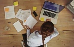 overview shot of an office desk with a brunette working on her laptop